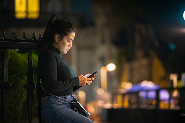 Woman using mobile phone to play a game outdoors at night